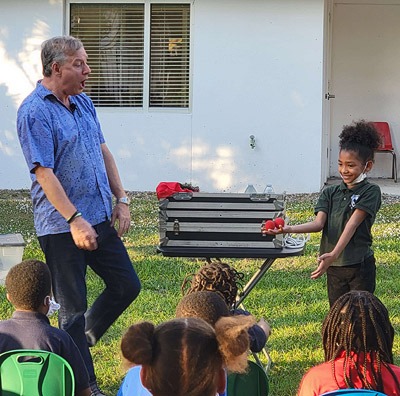 Tampa Bay area preschool magician for hire Timothy Pitch and a child performing outdoors